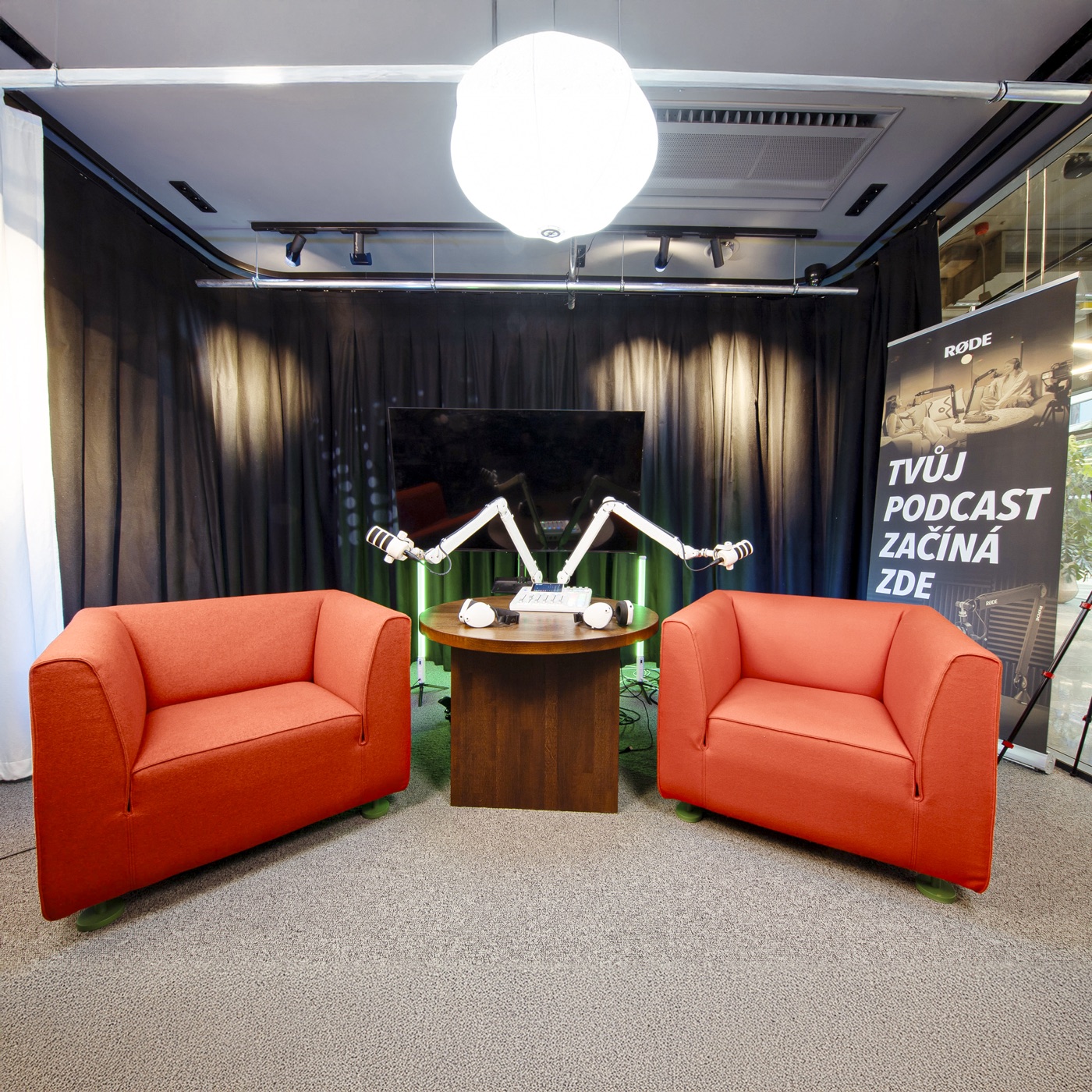 Podcastové studio s mikrofony a červenými křesly